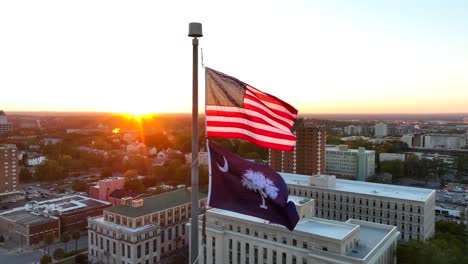American-and-South-Carolina-flags-waving-atop-capitol-building-in-downtown-Columbia,-SC