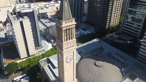 Aerial-pullback-above-Brisbane-City-Hall-clock-tower-at-midday,-shadows-from-skyscrapers
