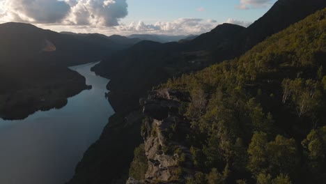 Hikers-stand-on-an-overhanging-rock-and-observe-a-majestic-Norwegian-fjord-from-a-mountain-cliff