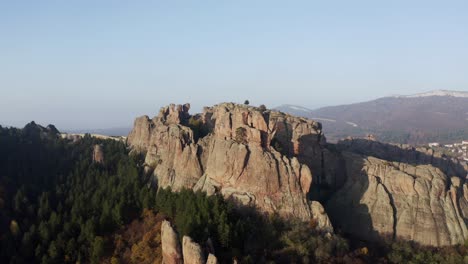 Pulling-away-and-slowly-retreating-from-the-Belogradchik-rock-formations,-and-revealing-the-town-and-the-Balkan-mountain-range-in-the-background,-in-the-province-of-Vidin-in-Bulgaria