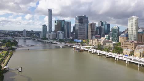 Drone-dolly-tilt-up-reveals-Brisbane-Australia-skyline-in-shadow-of-clouds