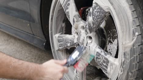 Cleaning-a-silver-wheel-on-a-black-car