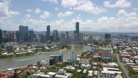 Aerial-establishing-overview-of-Brisbane-suburb-on-riverside-bank-across-bridge