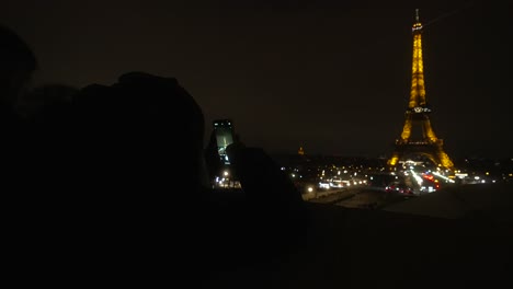 Persona-Tomando-Una-Foto-De-La-Torre-Eiffel-Con-El-Celular-En-Medio-De-La-Noche