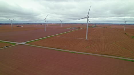 Atemberaubende-Luftaufnahme-Von-Windkraftanlagen-Inmitten-Eines-Bepflanzten-Feldes,-Die-Alternative-Energie-Erzeugen