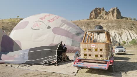 Man-holds-neck-of-hot-air-balloon-to-inflate-envelope-tourist-activity