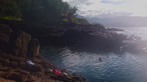 Kardanische-Weitschwenkaufnahme-Von-Menschen,-Die-Im-Queen&#39;s-Bath-Zwischen-Alten-Lavafelsen-An-Der-Nordküste-Von-Kaua&#39;i-In-Hawaii-Schwimmen