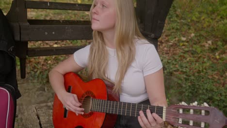Beautiful-female-songwriter-guitarist-rehearses-by-old-wishing-well