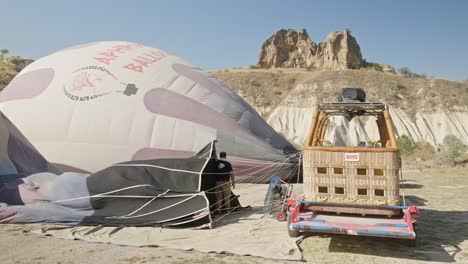 Hombre-Inflando-Globos-Aerostáticos-Turísticos-Sobre-Día-Soleado-Zona-Montañosa