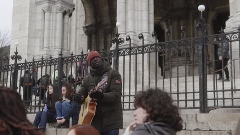 Person-singing-with-guitar-at-the-door-of-the-sacred-heart-of-Paris