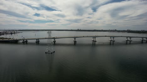 Hathaway-Bridge,-Panama-City,-Florida---Vehicles-Crossing-a-Bridge-that-Spans-Across-a-Waterway---Aerial-Drone-Shot