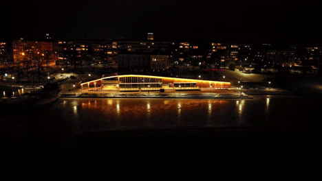 Aerial-view-away-from-the-illuminated-Fiskets-hus-building,-night-in-Vaasa,-Finland