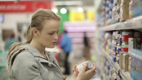 Una-Joven-Elige-Comida-Para-Su-Hijo-En-El-Supermercado.