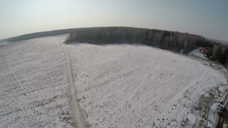 Village-with-vast-snowy-fields-near-the-forest-aerial-view