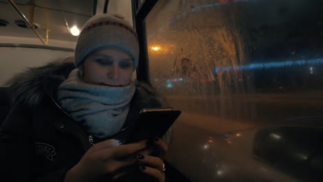 Mujer-Usando-Celular-Mientras-Viaja-En-Autobús-En-La-Ciudad-De-Noche