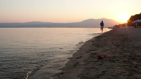 Man-running-along-a-beach-at-sunset