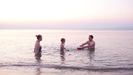 Young-family-playing-red-toy-boat-at-sunset