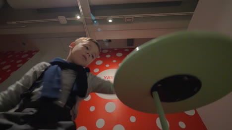 Kid-playing-with-spinning-disc-at-the-exhibition-of-Yayoi-Kusama