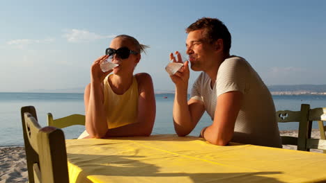 Young-couple-enjoying-drinks-at-the-seaside