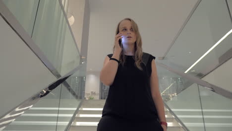 Una-Mujer-Joven-Hablando-Con-Un-Teléfono-Inteligente-Mientras-Baja-Las-Escaleras