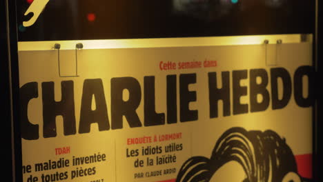 Banner-of-Charlie-Hebdo-satirical-magazine-in-night-street-of-Paris-France