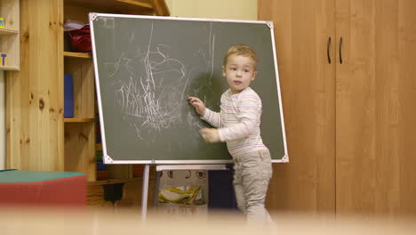 Kleiner-Junge-Zeichnet-Im-Kindergarten-Auf-Einer-Tafel
