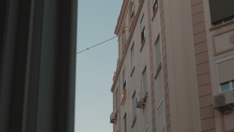 Apartment-house-with-closed-windows-and-Spanish-flag