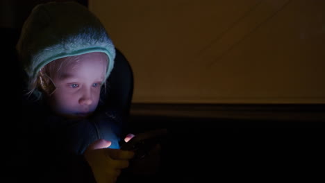 Night-car-trip-and-child-playing-games-on-the-phone