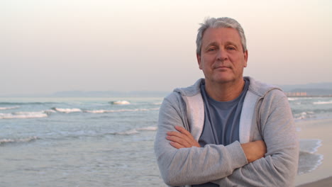 Sporty-retired-man-with-arms-crossed-portrait-on-the-beach
