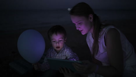 Niño-Con-Mamá-En-La-Playa-Por-La-Noche