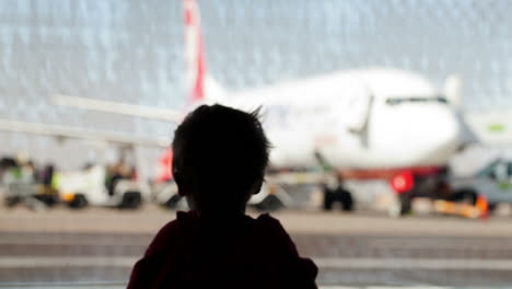 Kleiner-Junge-Beobachtet-Flugzeuge-Am-Flughafen