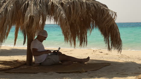 Man-using-laptop-on-the-beach