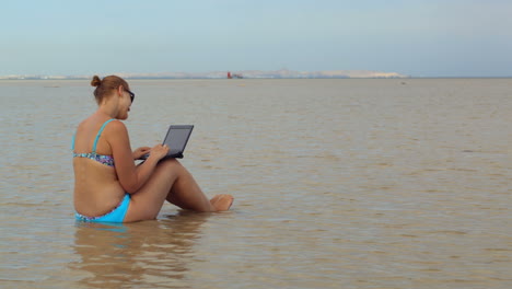 Frau-Mit-Laptop-Sitzt-Im-Meer