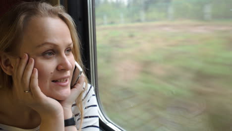 Young-woman-talking-on-the-phone-while-traveling-by-train