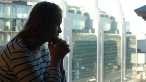 Traurige-Frau,-Die-Tief-In-Gedanken-Versunken-Ist-Und-Dann-Aus-Dem-Fenster-Mit-Blick-Auf-Die-Stadt-Schaut