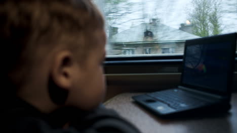 Junge-Schaut-Sich-Im-Zug-Einen-Film-Oder-Einen-Zeichentrickfilm-Auf-Einem-Laptop-An