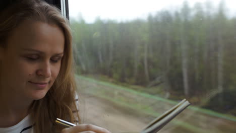 Mujer-Joven-Tomando-Notas-Mientras-Viaja-En-Tren.