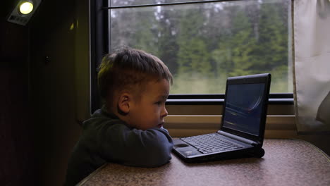 Kleiner-Junge-Im-Zug,-Der-Sich-Ein-Video-Auf-Dem-Laptop-Ansieht
