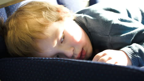 Little-boy-lying-on-the-seat-in-bus-car-ot-train
