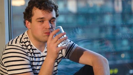 Man-drinking-water-sitting-by-the-window