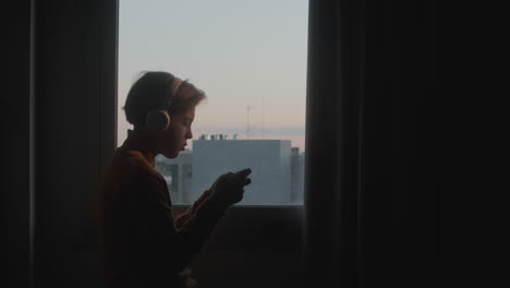 Teenager-gaming-near-sunrise-window