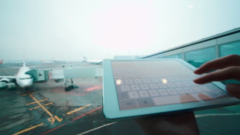 Usando-Una-Tableta-Junto-A-La-Ventana-En-El-Aeropuerto