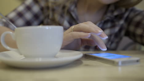 Woman-stirring-coffee-and-typing-sms