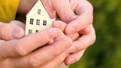 Couple-holding-a-small-toy-house-in-hands