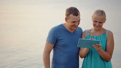 Young-couple-using-tablet-computer-by-the-sea
