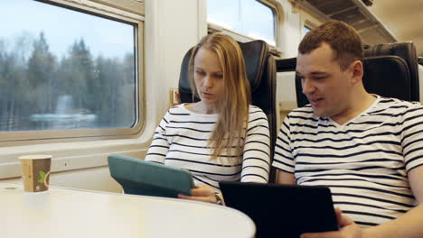 Young-people-talking-in-the-train-looking-on-tablet-PC
