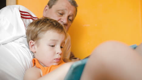 Boy-playing-on-pad-and-talking-to-grandfather