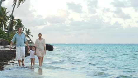 Parents-and-child-walking-along-the-beach-holding-hands