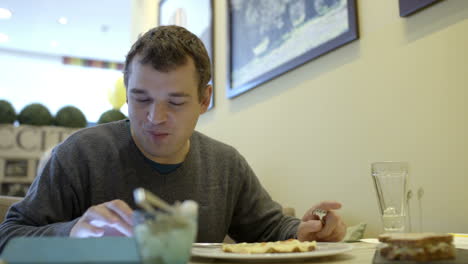 Man-with-touch-pad-eating-in-cafe