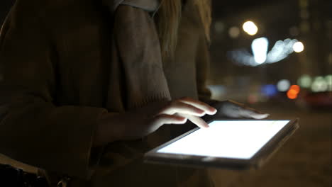 Woman-walking-in-the-evening-street-and-using-tablet-computer